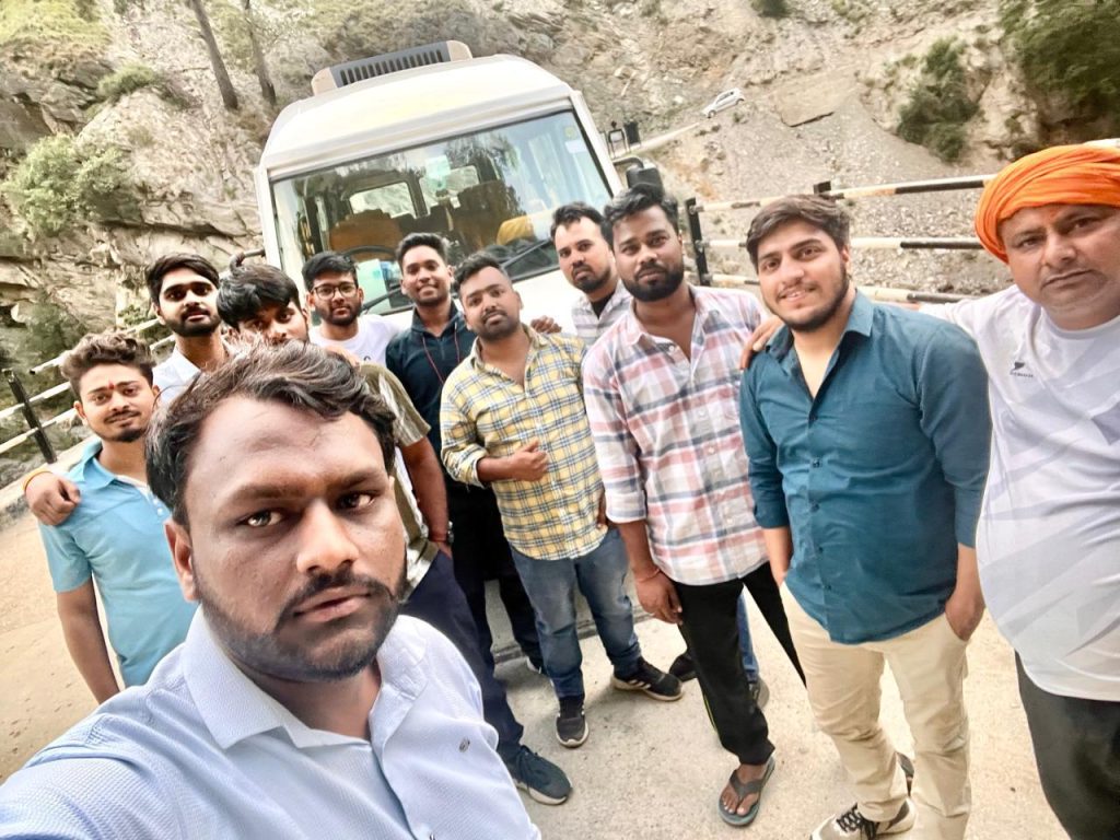 Group selfie with a Tempo Traveller on a hill road