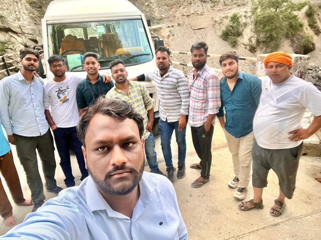 Group selfie of travelers with a Tempo Traveller in the mountains