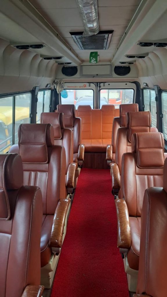 AC Tempo Traveller interior with brown leather push-back seats and red carpet